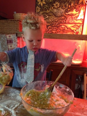 Lijah stirring batter in front of the chicks and their red heat lamp