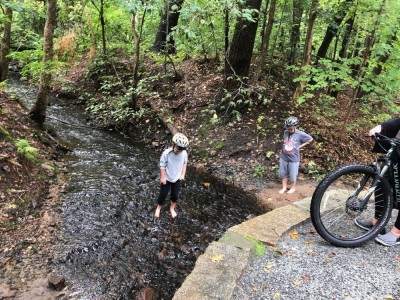 Zion and Elijah wading in a stream by the bike path