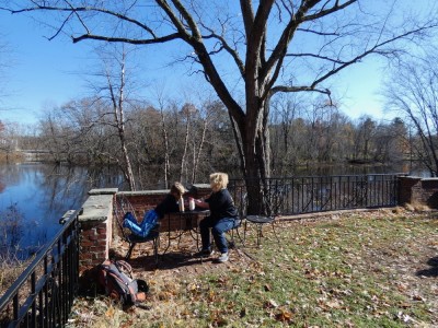 Harvey and Elijah eating lunch at a table on a lawn over the Concord River
