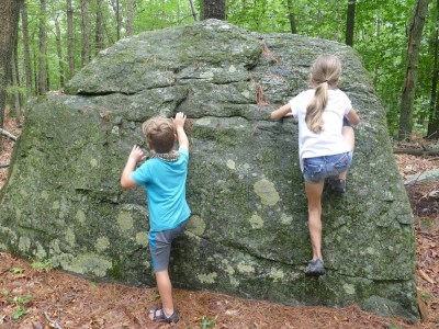 Elijah and a friend climbing up a boulder