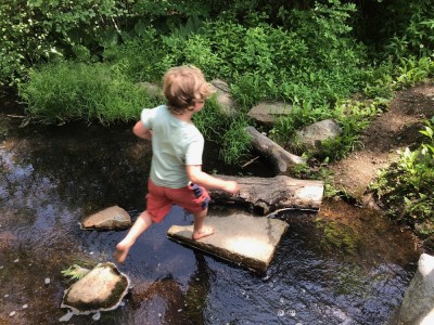 Elijah running across a little stream on stepping stones