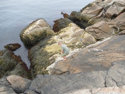 Elijah climbing down giant rocks to the ocean