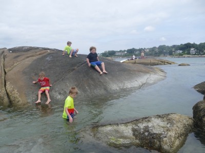 the boys sliding down a smooth rock into the water