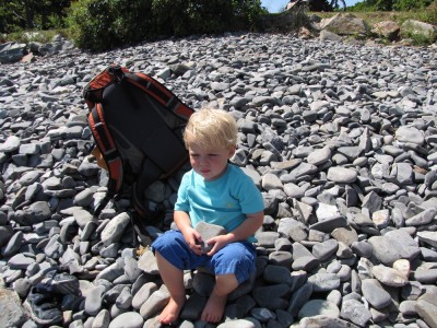 Zion sitting on the cobbles with a rock and a serious expresion