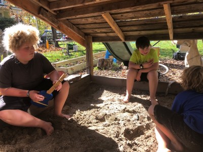 Harvey, Zion, and a friend sitting in our sandbox on a sunny day