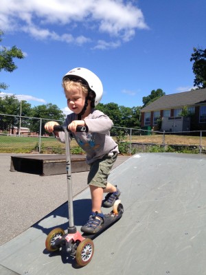 Zion riding his scooter down one of the ramps at the skate park