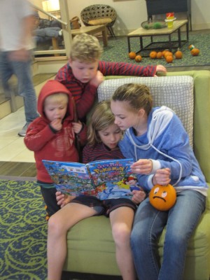 Harvey, Zion, Elle, and Reed looking at a book together