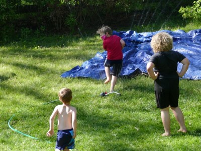 the boys playing with the sprinkler and tarp slip-and-slide