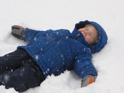 Zion on his back making a snow angel, with snow falling on his face