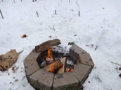 a fire burning in the firepit surrounded by snow