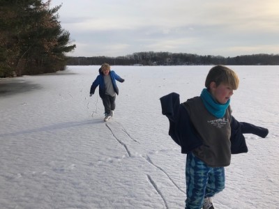 Zion and Elijah skating on a snowy pond