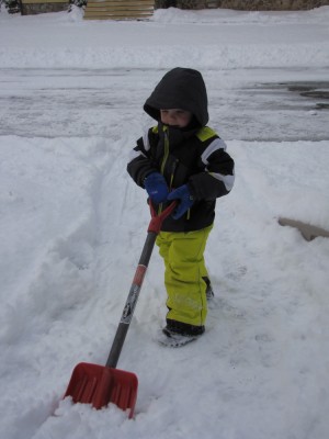 Zion in snowsuit shoveling the front walk