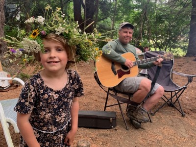 a child in a solstice crown of flowers, and me playing guitar