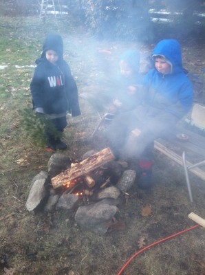 the boys standing around a smoky fire