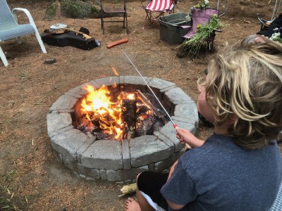 Elijah toasting a hotdog over a fire