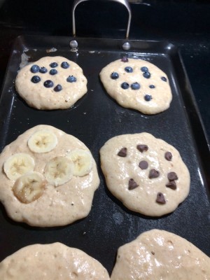 pancakes on the griddle: blueberry, chocolate chip, banana, and plain
