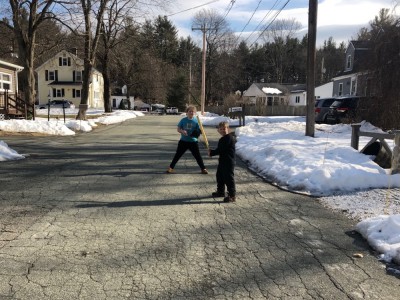Harvey and Zion playing baseball in the street with snow on the lawns