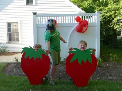 the boys posing with big plywood strawberry cutouts