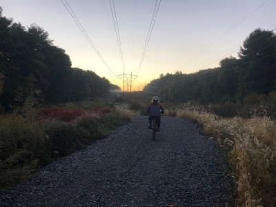 Harvey riding up a gravel road towards a misty sunrise