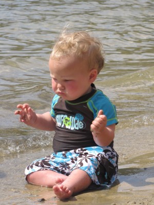 Elijah sitting at the edge of the water in his swimsuit