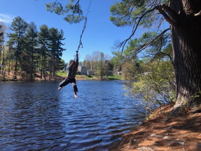 Elijah swinging on a rope swing over a pond