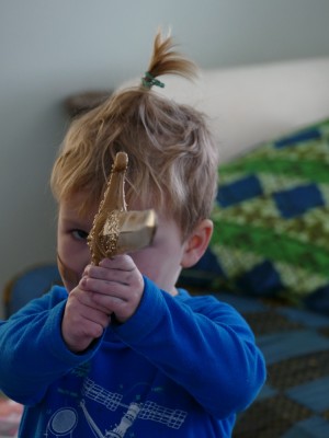 Lijah with a rubber band in his hair pointing a sword like a gun