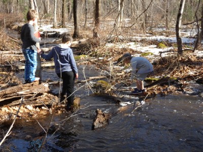Zion, Elijah, and a friend playing by a rushing stream
