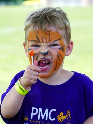 Lijah in tiger face paint roaring while holding a lollipop