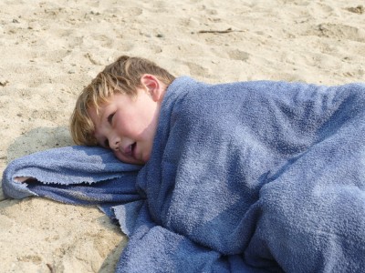 Elijah cuddling in his towel on the beach