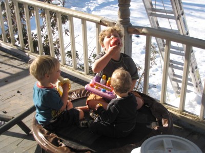 all three boys, in summery clothes, having a snack on the porch