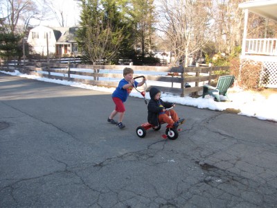 Harvey pushing Zion in Lijah's new tricycle