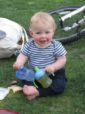 Zion on the grass with two sippy cups