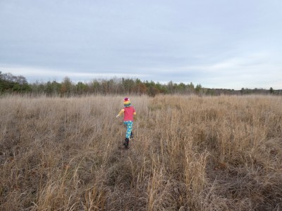 Elijah running in a november-colored field wearing bright clothes