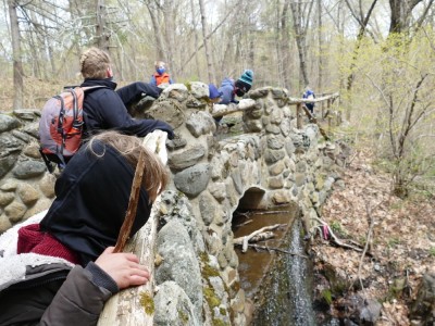 the boys looking over a stone bridge at a trickly waterfall