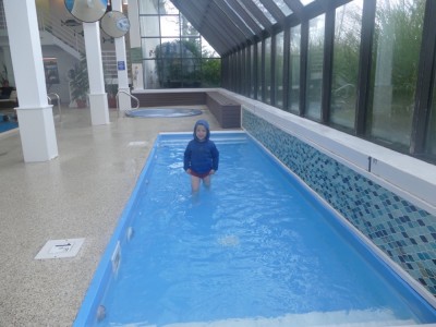 Zion, fully dressed, wading in the indoor baby pool