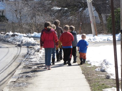 a gang of kids walking down the sidewalk