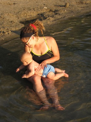 Leah holding Lijah in her lap, in swimming posture, in the pond
