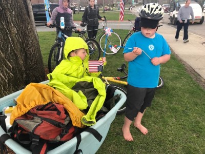 Lijah bundeled up in the cargo bike, Harvey on his bike in a raincoat