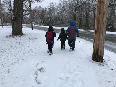 the boys walking along the sidewalk in the snow