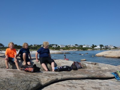 the boys sitting on a big rock on the beach