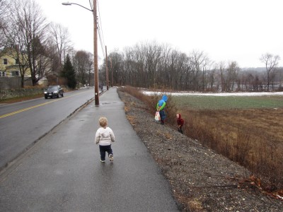 the boys walking on the sidewalk by a fallow field