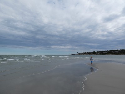 Elijah standing at the end of a sand spit among waves
