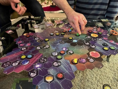 a close of up hands moving pieces on the board game Wormholes