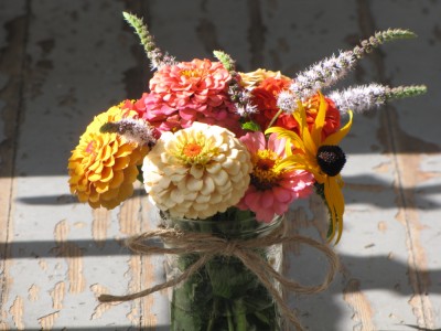 some zinnias and other flowers in a half-pint jar
