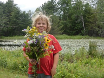 Zion holding a big bouquet of wildflowers in front of a waterlily pond